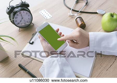 Stock Image - Doctor using smartphone.. Fotosearch