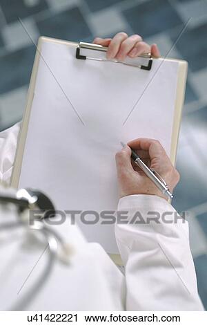 Stock Image - Doctor writing on clipboard.. Fotosearch