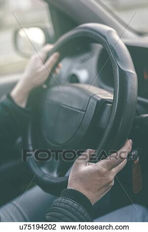 Stock Image - Driver's hands on steering wheel, close-up.. Fotosearch