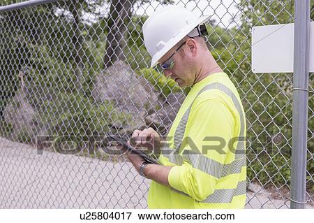 Stock Photo - Engineer at an electric power plant checking his tablet.. Fotosearch