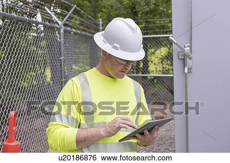 Stock Photograph - Engineer at an electric power plant checking his tablet.. Fotosearch