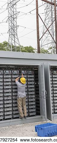 Engineer connecting energy storage batteries for backup power to an electric power plant. View Large Photo Image Picture - Engineer connecting energy storage batteries for backup power to an electric power plant.. Fotosearch