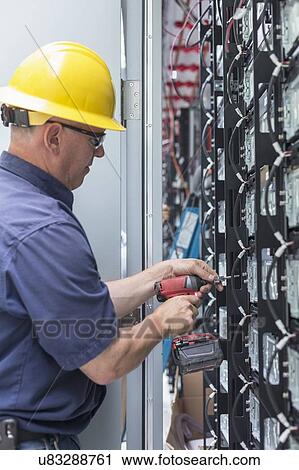 Stock Image - Engineer connecting energy storage batteries for backup power to an electric power plant.. Fotosearch