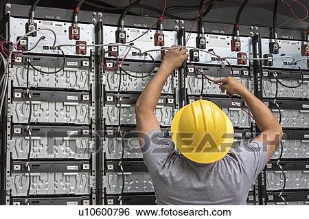 Stock Photograph - Engineer connecting energy storage batteries for backup power to an electric power plant.. Fotosearch