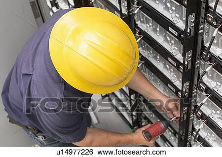 Stock Photograph - Engineer connecting energy storage batteries for backup power to an electric power plant.. Fotosearch