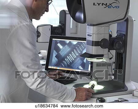 Engineer using a stereo microscope to inspect a manufactured component during the quality control process. View Large Photo Image Picture - Engineer using a stereo microscope to inspect a manufactured component during the quality control process.. Fotosearch