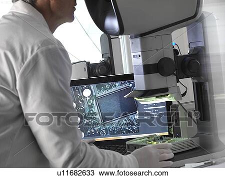 Stock Image - Engineer using a stereo microscope to inspect a printed circuit board during the quality control process.. Fotosearch