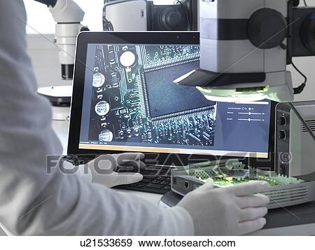 Stock Photo - Engineer using a stereo microscope to inspect a printed circuit board during the quality control process.. Fotosearch
