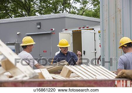Stock Image - Engineers putting pallets into a dumpster.. Fotosearch