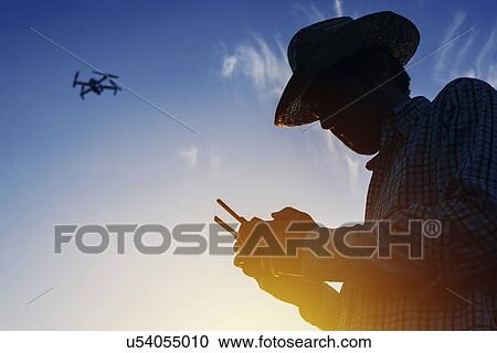 Stock Image - Farmer piloting drone.. Fotosearch
