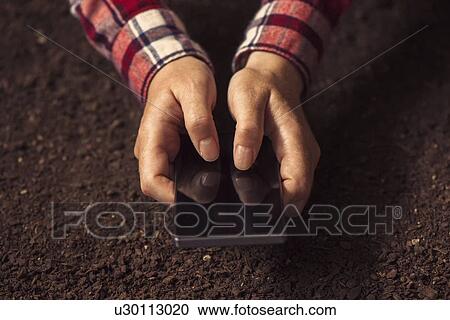 Stock Image - Farmer using smartphone.. Fotosearch