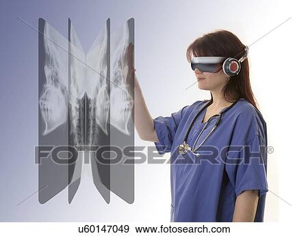 Stock Photo - Female doctor wearing virtual reality headset and examining X-rays.. Fotosearch