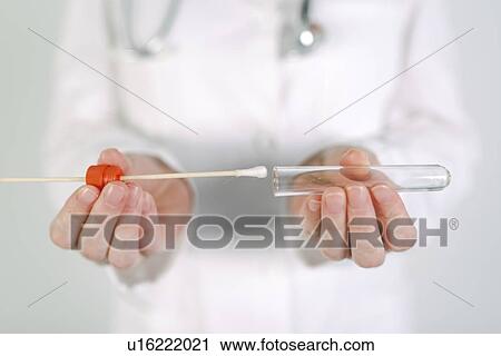 Stock Image - Female forensic technician collecting biological specimen.. Fotosearch