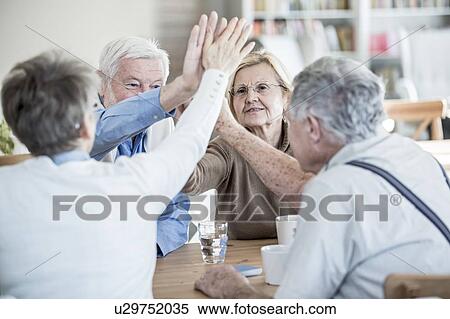 Friends giving high fives in retirement home. View Large Photo Image Stock Photography - Friends giving high fives in retirement home.. Fotosearch
