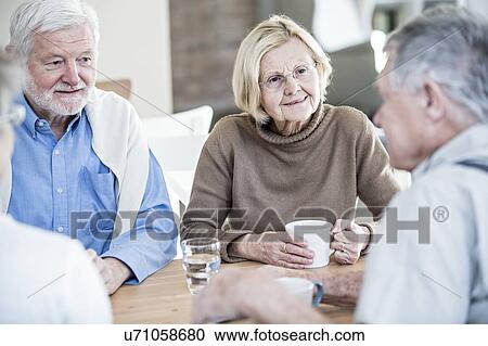 Stock Image - Friends talking in retirement home.. Fotosearch