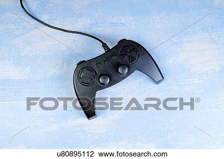 Stock Image - Game pad controller on wooden desk, flat lay top view.. Fotosearch