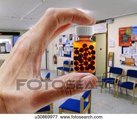 Stock Photo - Hand holding pill bottle in waiting room.. Fotosearch