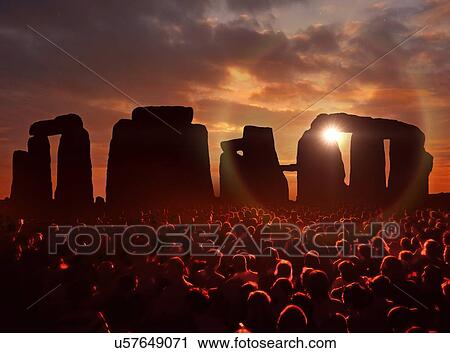Stock Image - Illustration of a gathering of people in front of Stonehenge in Wiltshire, UK, during sunset.. Fotosearch