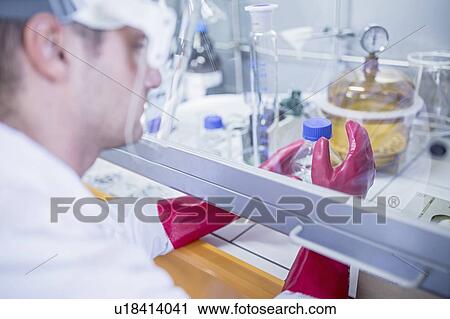 Lab technician using a laminar flow hood, thick gloves and a face shield while working with dangerous chemicals. View Large Photo Image Stock Image - Lab technician using a laminar flow hood, thick gloves and a face shield while working with dangerous chemicals.. Fotosearch