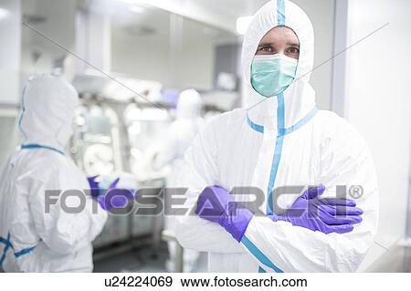 Stock Photo - Lab technician wearing a protective suit and face mask in a laboratory that must maintain a sterile environment.. Fotosearch