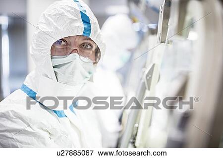 Stock Photo - Lab technician wearing a protective suit, face mask and safety goggles in a laboratory that must maintain a sterile environment.. Fotosearch