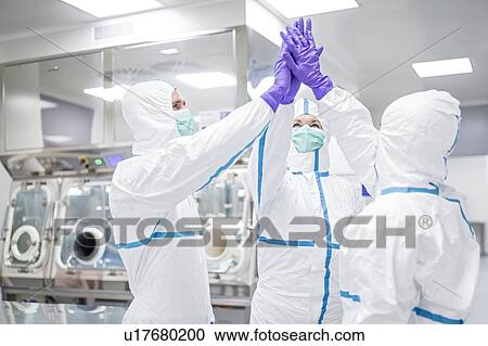 Stock Image - Lab technicians in a sterile environment high-fiving.. Fotosearch