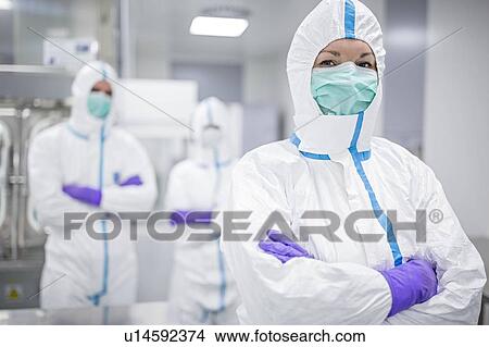 Picture - Lab technicians wearing protective suits and face masks in a laboratory that must maintain a sterile environment.. Fotosearch