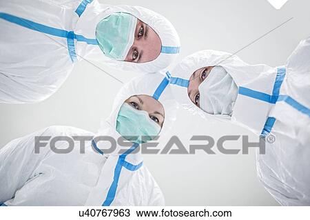 Stock Image - Lab technicians wearing protective suits and face masks in a laboratory that must maintain a sterile environment.. Fotosearch