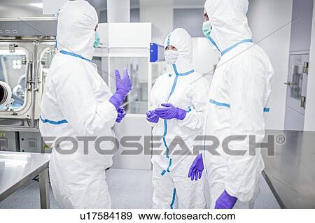 Stock Photo - Lab technicians wearing protective suits and face masks in a laboratory that must maintain a sterile environment.. Fotosearch