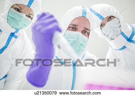 Lab technicians wearing protective suits and face masks in a laboratory that must maintain a sterile environment. View Large Photo Image Stock Photo - Lab technicians wearing protective suits and face masks in a laboratory that must maintain a sterile environment.. Fotosearch