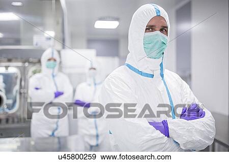Stock Photo - Lab technicians wearing protective suits and face masks in a laboratory that must maintain a sterile environment.. Fotosearch