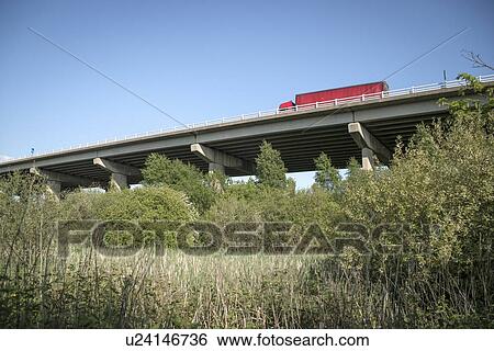 Stock Photograph - M56 Motorway passing over marshes between River Weaver and the Weaver Navigation, Frodsham, Cheshire, UK.. Fotosearch
