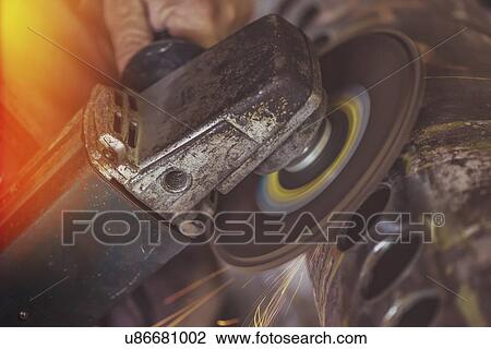 Stock Image - Man using metal grinder.. Fotosearch