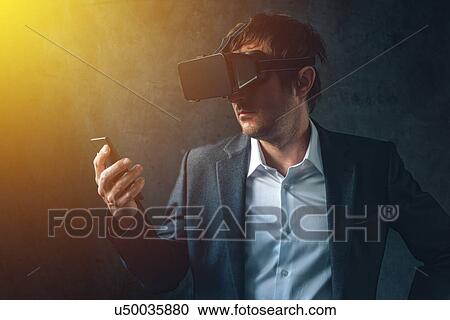 Stock Image - Man with VR headset exploring virtual reality.. Fotosearch
