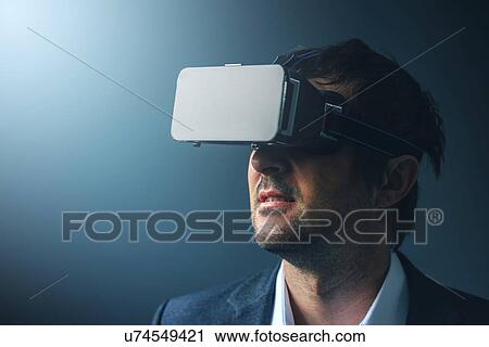Stock Image - Man with VR headset exploring virtual reality.. Fotosearch