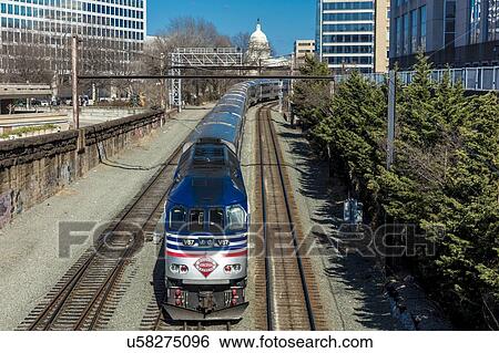Stock Photograph - Passenger train with US Capitol in background approaches L'enfant Plaza Station, Washington D. C.. Fotosearch