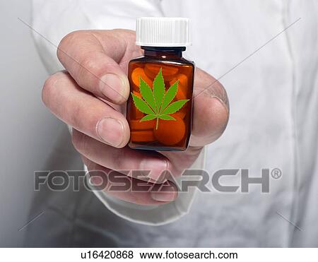 Stock Photo - Person holding pill bottle containing medicinal marijuana.. Fotosearch