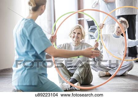 Physiotherapist with two senior women holding plastic hoops. View Large Photo Image Picture - Physiotherapist with two senior women holding plastic hoops.. Fotosearch