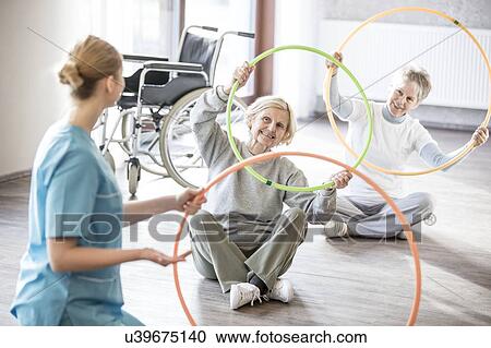 Physiotherapist with two senior women holding plastic hoops. View Large Photo Image Stock Image - Physiotherapist with two senior women holding plastic hoops.. Fotosearch