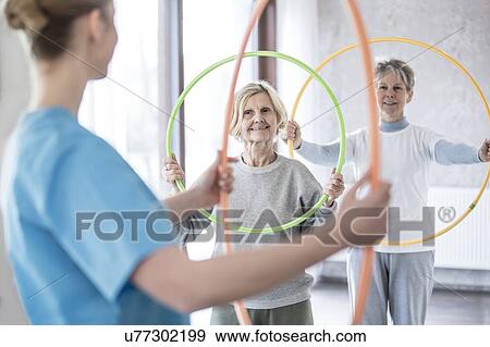 Physiotherapist with two senior women holding plastic hoops. View Large Photo Image Stock Photo - Physiotherapist with two senior women holding plastic hoops.. Fotosearch