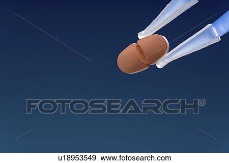 Stock Photo - Pill held between tweezers.. Fotosearch