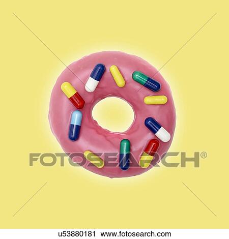 Stock Image - Pink doughnut with capsules, studio shot.. Fotosearch