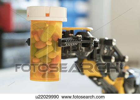 Stock Image - Robotic arm holding bottle of pills.. Fotosearch
