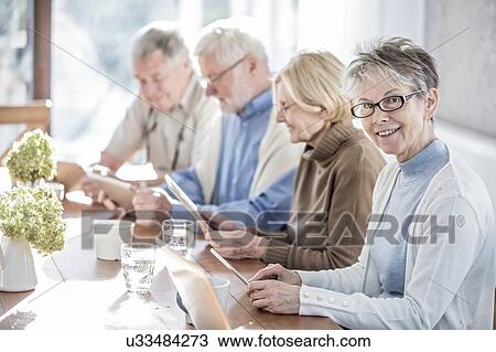 Stock Image - Senior adults in care home using digital tablets.. Fotosearch