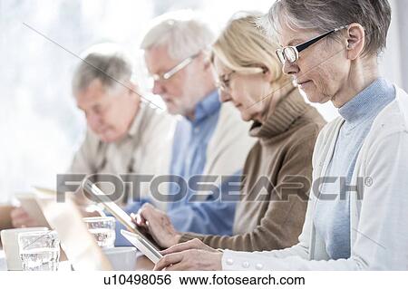 Stock Photograph - Senior adults in care home using digital tablets.. Fotosearch