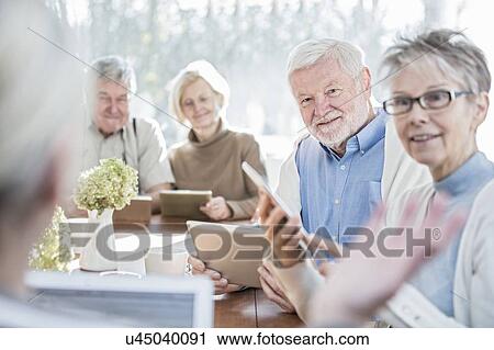 Stock Image - Senior adults in care home with digital tablets.. Fotosearch