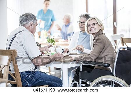 Stock Image - Senior adults in care home, woman in wheelchair.. Fotosearch