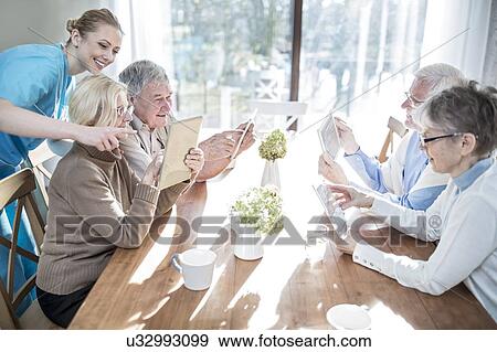 Stock Photo - Senior adults using digital tablets in care home.. Fotosearch