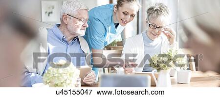 Stock Photo - Senior adults using digital tablets in care home.. Fotosearch