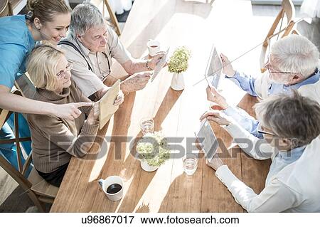 Stock Photo - Senior adults using digital tablets in care home.. Fotosearch